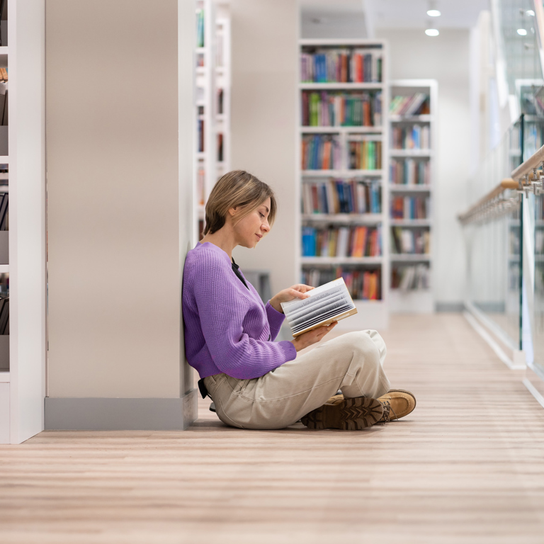 Een persoon leest een boek in een bibliotheek