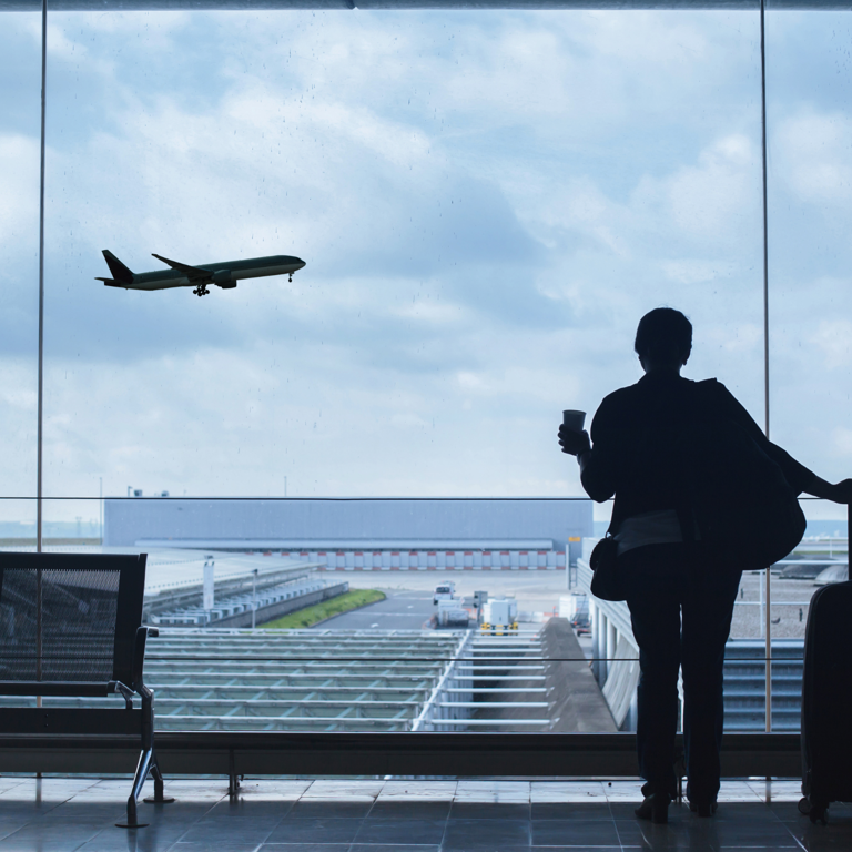 Een persoon kijkt uit het raam op een luchthaven